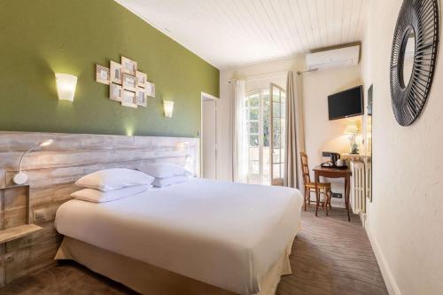 a bedroom with a large white bed and a desk at Best Western Le Val Majour in Fontvieille