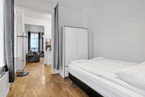 um quarto branco com uma cama grande e uma secretária em Sunny Central Reykjavík Apartment em Reiquiavique