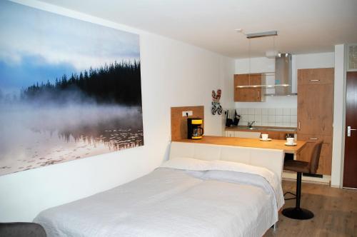 Dormitorio con cama, escritorio y pintura en Ferienwohnung mit Aussicht, en Enzklösterle