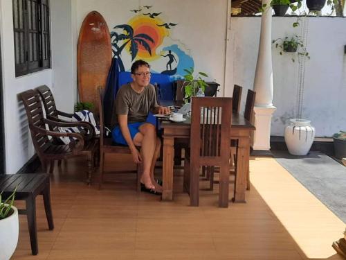 un hombre sentado en una mesa en una habitación en Ashen's Beach House, en Busse