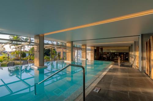 an indoor swimming pool in a building with glass walls at Enotel Magnólia in Funchal