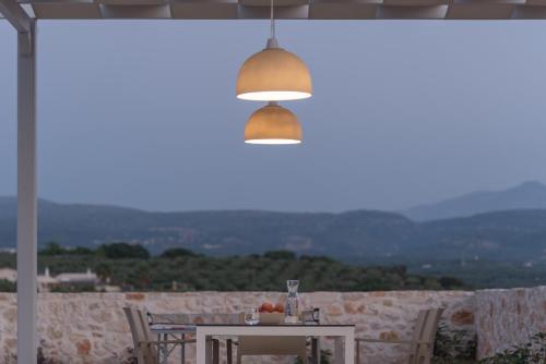 a table with chairs and a light hanging from a ceiling at Evaero Villas I, II, III, IV, Family Retreats, By ThinkVilla in Sfakaki