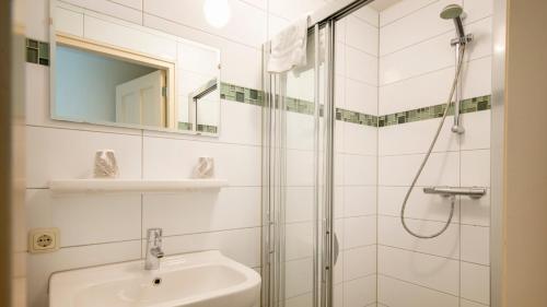 een witte badkamer met een wastafel en een douche bij Appartementen Natuurlijk in Egmond aan Zee