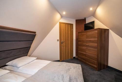 a small bedroom with a bed and a wooden cabinet at GORSKI RESORT Lux Apartments Jacuzzi & Sauna in Poronin