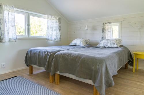 a bedroom with a bed and two windows at Strandby Villas Käringsund in Eckerö