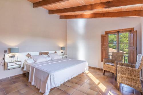 a bedroom with a bed and two chairs and a window at Es turo de Cabrera in Ses Salines