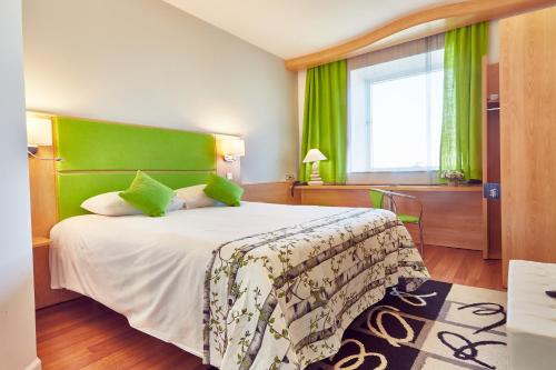 a bedroom with a large bed with a green headboard at MyContinental Sibiu in Sibiu