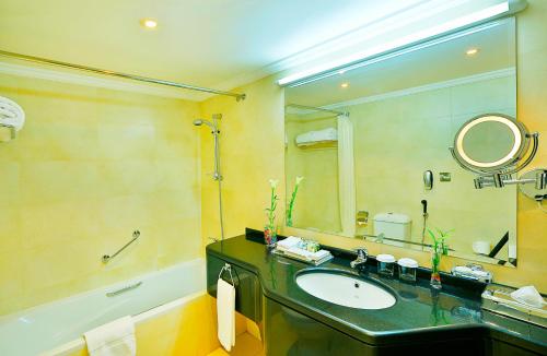 a bathroom with a sink and a mirror and a tub at All Seasons Hotel Al Ain - Previously City Seasons in Al Ain