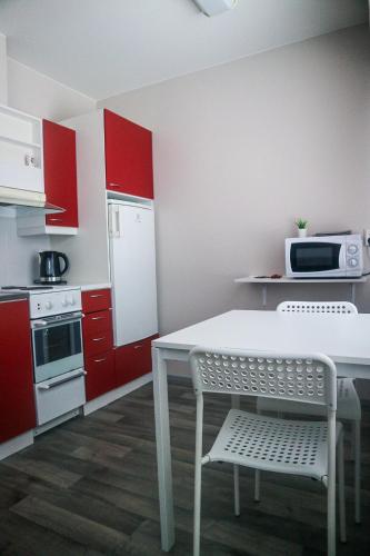 uma cozinha com armários vermelhos e uma mesa e cadeira brancas em Stay Kymi kalustetut huoneistot em Kouvola