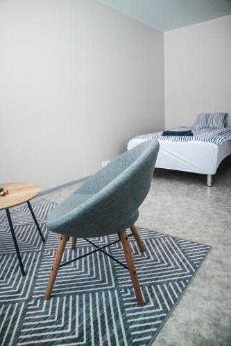 een woonkamer met een stoel en een bed bij Stay Kymi kalustetut huoneistot in Kouvola
