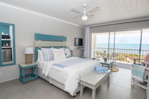 a bedroom with a bed and a balcony with the ocean at True North West Coast in St Helena Bay