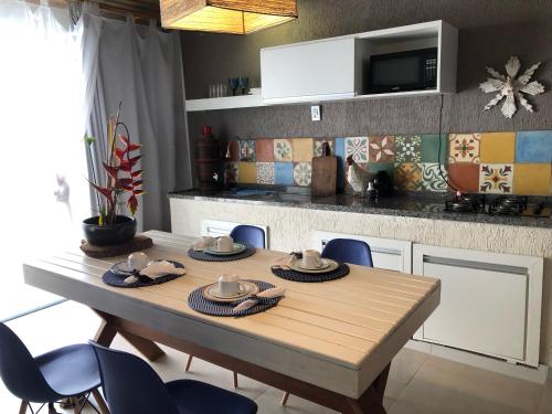 a table in a kitchen with blue chairs around it at Loft Caeté in Araruama