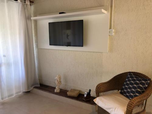 a living room with a chair and a television on a wall at Loft Caeté in Araruama