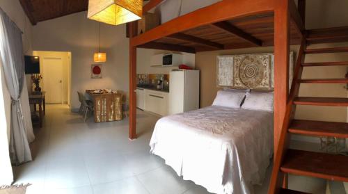 a bedroom with a white bed and a kitchen at Loft Caeté in Araruama