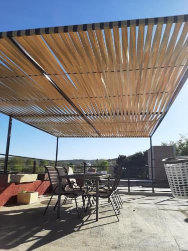 a patio with a table and chairs under a wooden canopy at Complejo Los Cipreses in Villa Carlos Paz