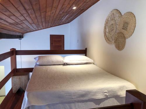 a bedroom with a bed with white sheets and a wooden ceiling at Loft Caeté in Araruama