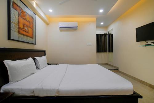 a bedroom with a large white bed and a tv at FabHotel Imperial Regency in Indore