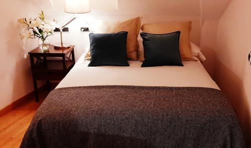 sypialnia z łóżkiem z czarnymi poduszkami i stołem w obiekcie Atico con Terraza, Plaza América w mieście Vigo