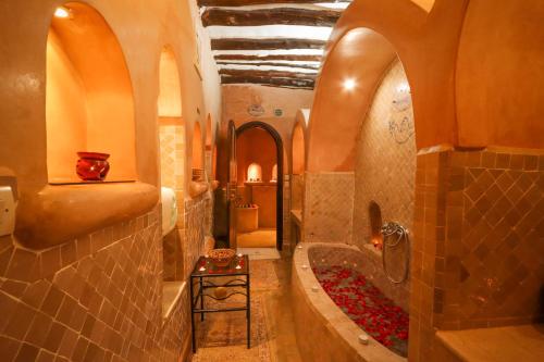 La salle de bains est pourvue d'une baignoire et d'une douche avec des fleurs rouges. dans l'établissement Riad Palais Des Princesses & Spa, à Marrakech