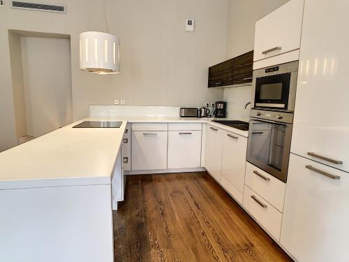 Il comprend une cuisine blanche avec des appareils électroménagers blancs et du parquet. dans l'établissement Le Cid 3P CIR3374, à Cannes