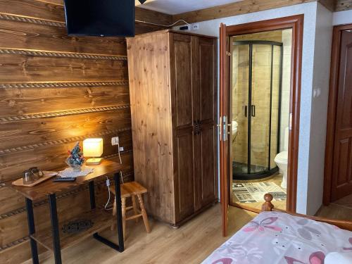 Schlafzimmer mit einer Holzwand, einem Schreibtisch und einem Bett in der Unterkunft Willa Dziubas z jacuzzi & sauną in Małe Ciche