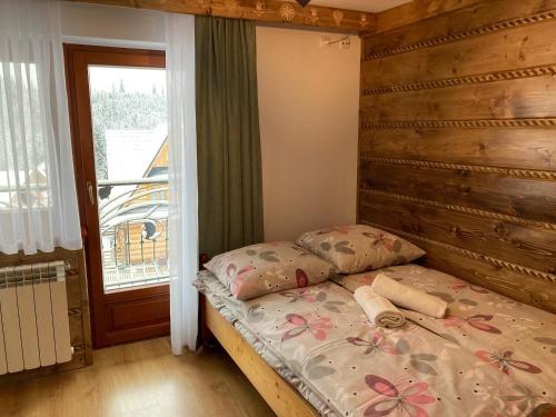 a bedroom with a bed with a wooden headboard and a window at Willa Dziubas z jacuzzi & sauną in Małe Ciche