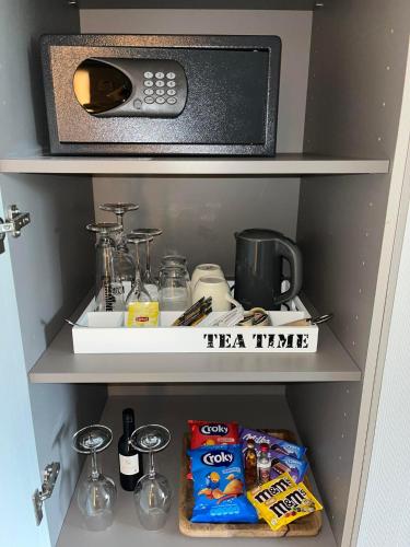 a kitchen shelf with a microwave and food and drinks at Hotel Gemeente Huis in Nieuwpoort