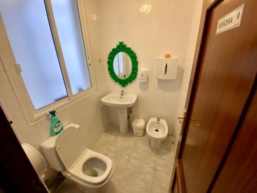 a bathroom with a toilet and a sink and a mirror at Hostal Alvarez in León