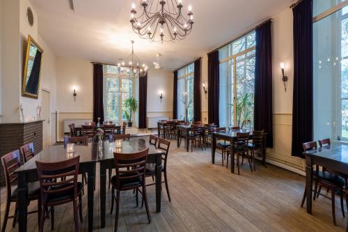 a restaurant with tables and chairs and a chandelier at Stayokay Hostel Utrecht - Bunnik in Bunnik