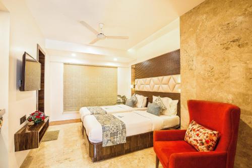 a hotel room with a bed and a red chair at Hotel Auris & Banquets, Mumbai International Airport in Mumbai