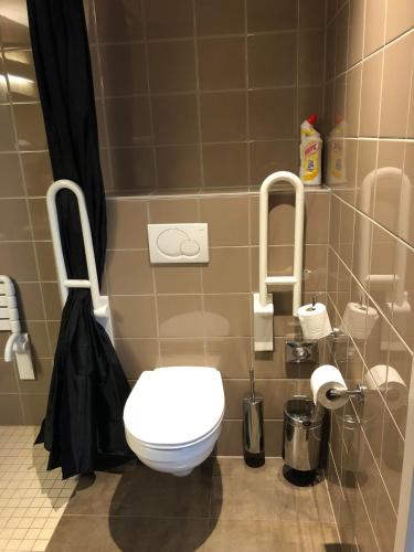 a bathroom with a white toilet and a black shower curtain at Hotel Gemeente Huis in Nieuwpoort