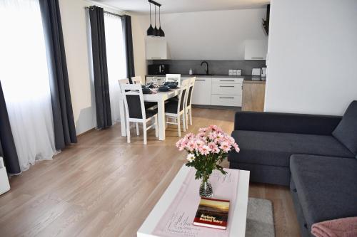 ein Wohnzimmer mit einem Sofa und einem Tisch mit Blumen in der Unterkunft Dwa Widoki Apartamenty in Zubrzyca Górna