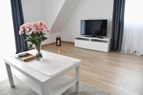 a living room with a white table with a vase of flowers at Dwa Widoki Apartamenty in Zubrzyca Górna