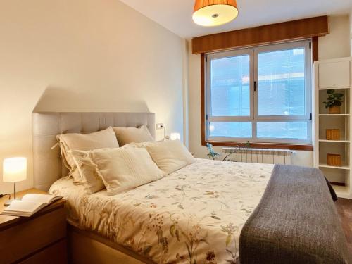Un dormitorio con una cama grande y una ventana en Orzan Beach Surf Apartment, en A Coruña