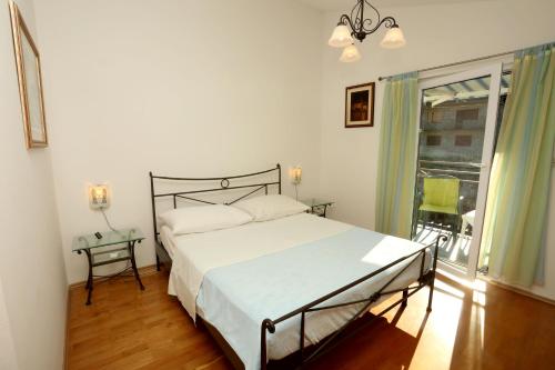 a bedroom with a white bed and a window at Apartments Sikirica in Trogir