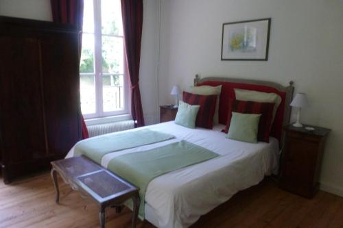 een slaapkamer met een groot bed en een raam bij Chambres d'Hôtes Le Bas Manoir in Bretteville-sur-Odon