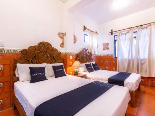 two beds in a room with white and blue at Capital O Posada La Casa De La Tia, Oaxaca in Oaxaca City