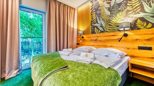 a bedroom with a green bed with a large window at Apartamenty VIP Centrum - Wczasowa 17 by Royal Aparts in Świeradów-Zdrój
