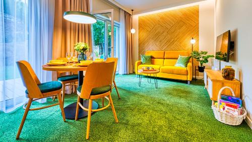 ein Wohnzimmer mit einem Tisch und einem gelben Sofa in der Unterkunft Apartamenty VIP Centrum - Wczasowa 17 by Royal Aparts in Świeradów-Zdrój