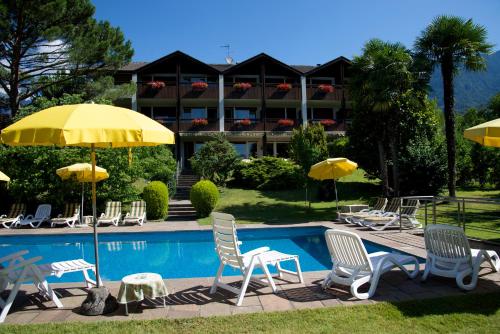 uma piscina com cadeiras e guarda-sóis em frente a um hotel em Hotel Tannerhof em Merano