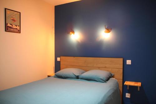 um quarto com uma cama com paredes azuis e duas luzes em Plein cœur Cauterets: Appartement 6/8 personnes em Cauterets