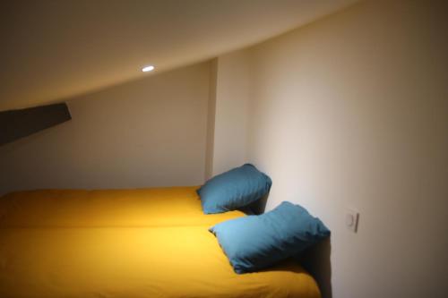 um quarto com uma cama com duas almofadas azuis em Plein cœur Cauterets: Appartement 6/8 personnes em Cauterets