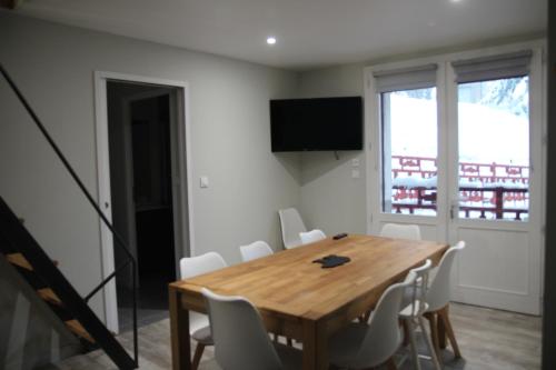 uma sala de jantar com uma mesa de madeira e cadeiras brancas em Plein cœur Cauterets: Appartement 6/8 personnes em Cauterets