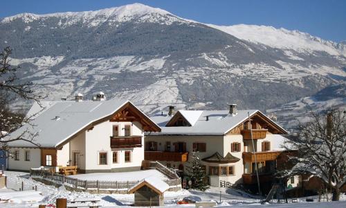 a house in the snow with a mountain in the background at Hof am Schloss Apartement Zirm in Montechiaro