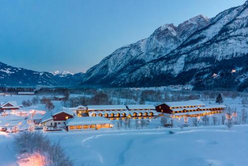 um edifício coberto de neve com montanhas ao fundo em Dolomitengolf Hotel & Spa em Lavant