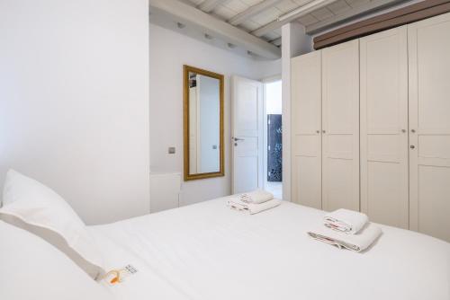 1 dormitorio blanco con 1 cama blanca grande y espejo en Cave Suite by LLB Villas - Sea & Sunset View, en Mykonos ciudad