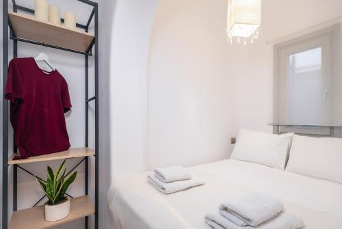 Un dormitorio con una cama blanca y una camisa roja en un estante en Cave Suite by LLB Villas - Sea & Sunset View en Mykonos