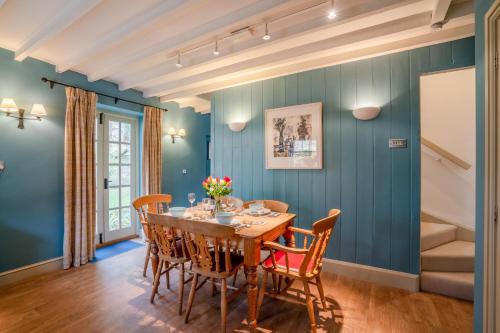 ein Esszimmer mit blauen Wänden und einem Holztisch und Stühlen in der Unterkunft Manor Lodge Cottage in Chipping Campden