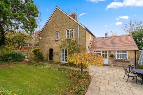 an old brick house with a patio and a yard at 2 Manor Lodge Cottages in Chipping Campden