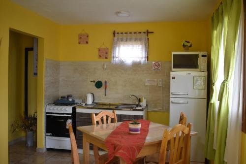 a kitchen with a table and a refrigerator and a stove at Cabañas "Las Margaritas" in Ushuaia
